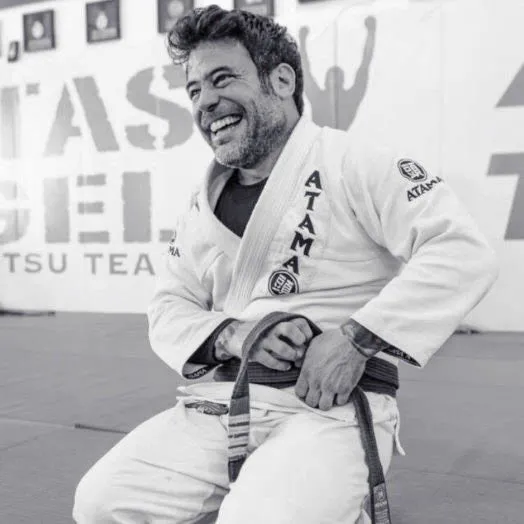 Professor Marcos "Parrumpa" DaMatta smiling on the mats in his gi and black belt