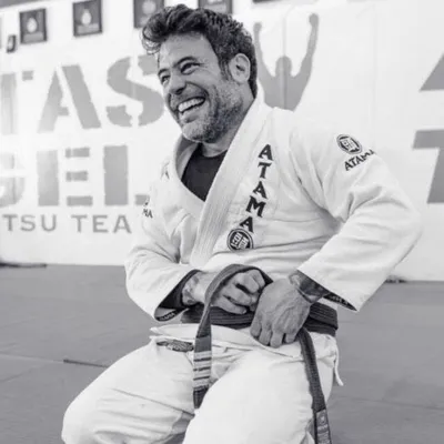 Professor Marcos "Parrumpa" DaMatta smiling on the mats in his gi and black belt